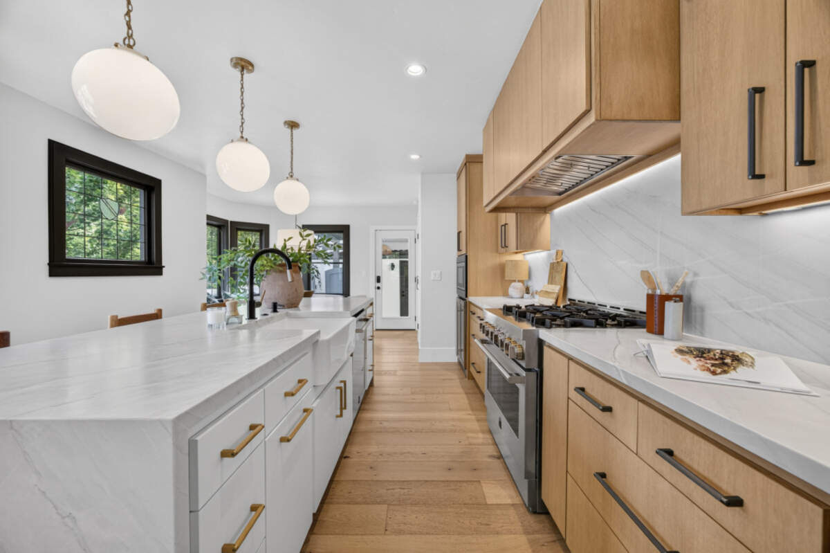 A completely reimagined kitchen holds custom cabinetry paired with leathered quartzite countertops and an expansive waterfall‑edge island that anchors the room.